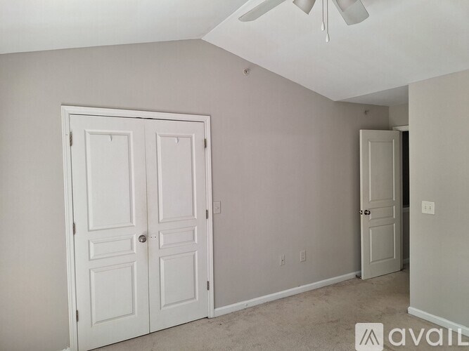 A room with a white ceiling fan and two white doors.