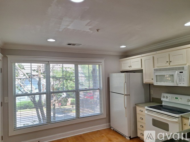 A kitchen with white appliances and wooden floors.
