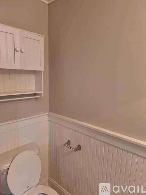 A white toilet in a bathroom with a cabinet above it.