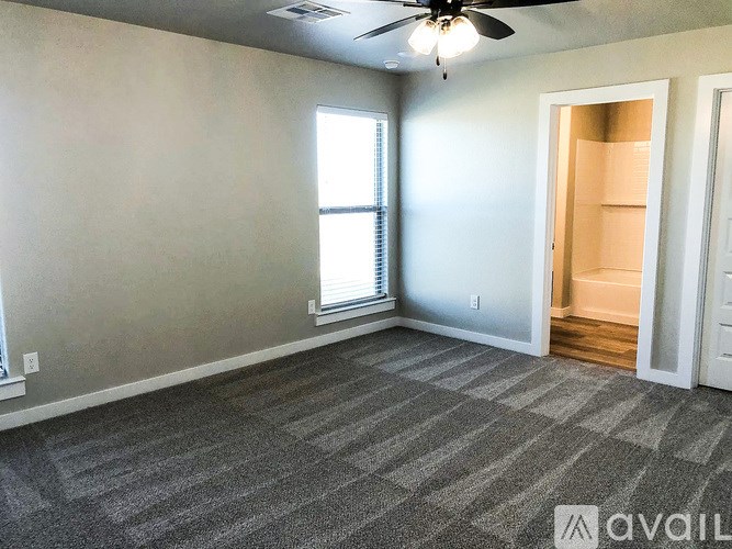 A room with a ceiling fan and a doorway leading to another room.