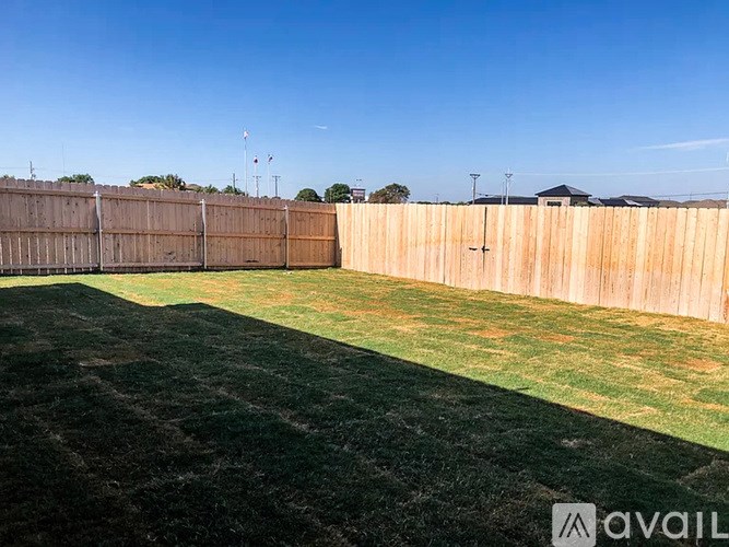 A backyard with a wooden fence and green grass.