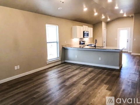 A spacious kitchen with wooden floors and a grey countertop.