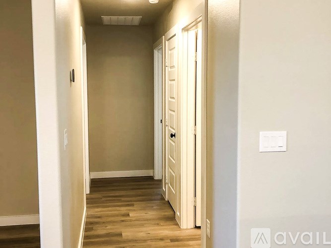 A hallway with a door on the right and a light switch on the wall.