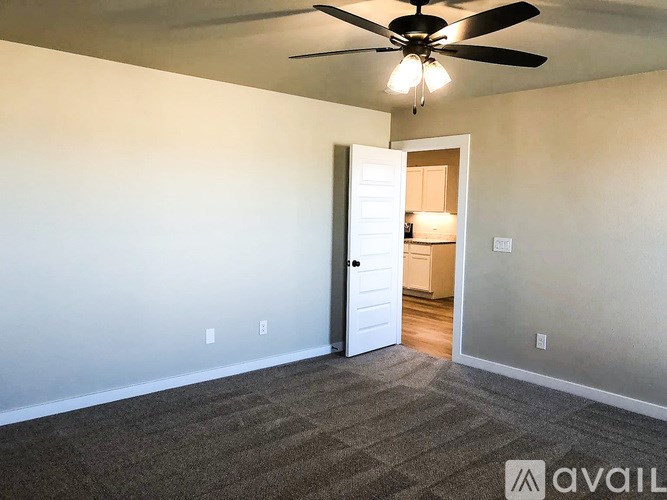 A room with a ceiling fan and a door leading to another room.
