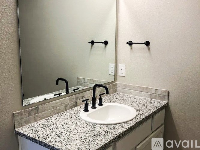 A bathroom sink with a granite counter top and a mirror above it.