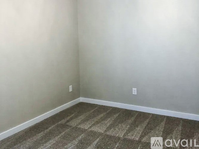 A room with a striped carpet and a wall socket.