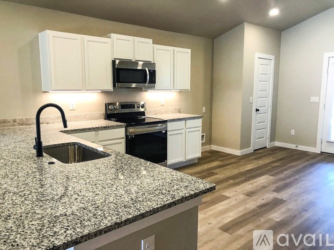 A kitchen with granite countertops and white cabinets.