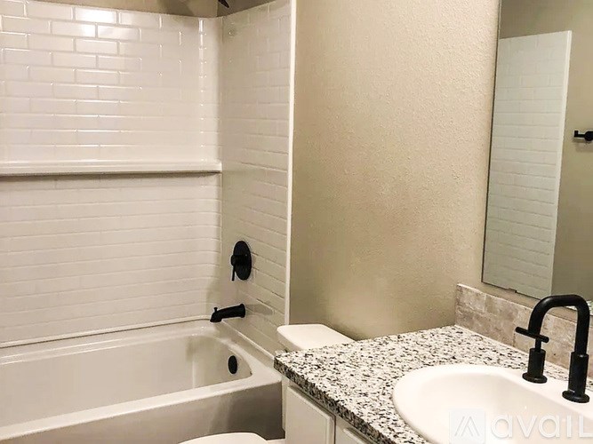 A white bathroom with a tub, sink and mirror.
