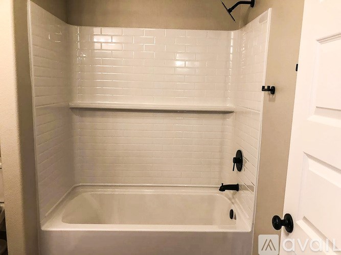 A white tiled bathroom with a white bathtub and a white door.