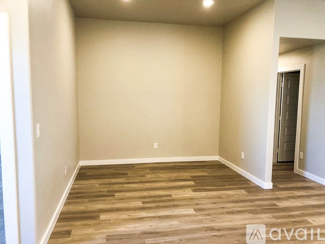 A room with wooden flooring and a door on the right.