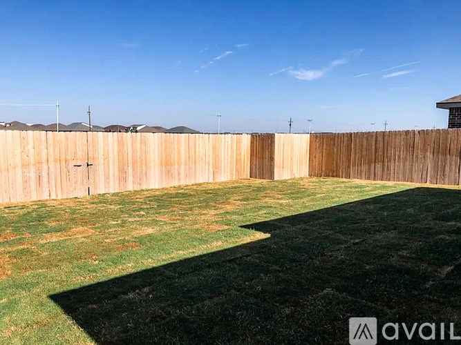 A backyard with a wooden fence and a green lawn.