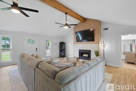 A living room with a grey couch and a television mounted on the wall.