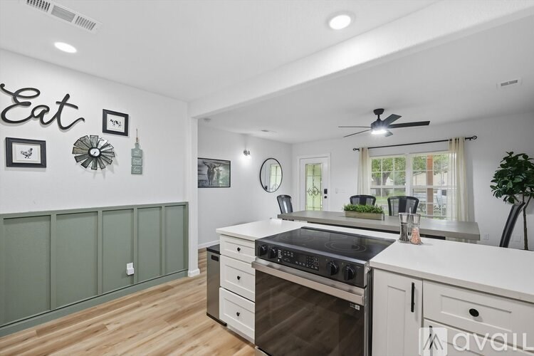 A kitchen with a stove top oven and a wall decoration that says "Eat".