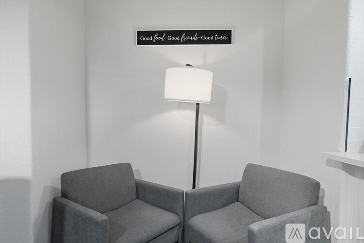 Two grey chairs are placed in front of a lamp and a sign that reads "Good feed, Good mood, Good times".