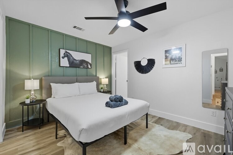 A bedroom with a bed, a ceiling fan, and a painting of a horse on the wall.