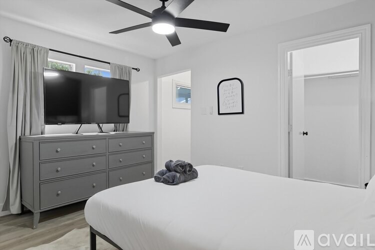 A bedroom with a bed, dresser, and television.