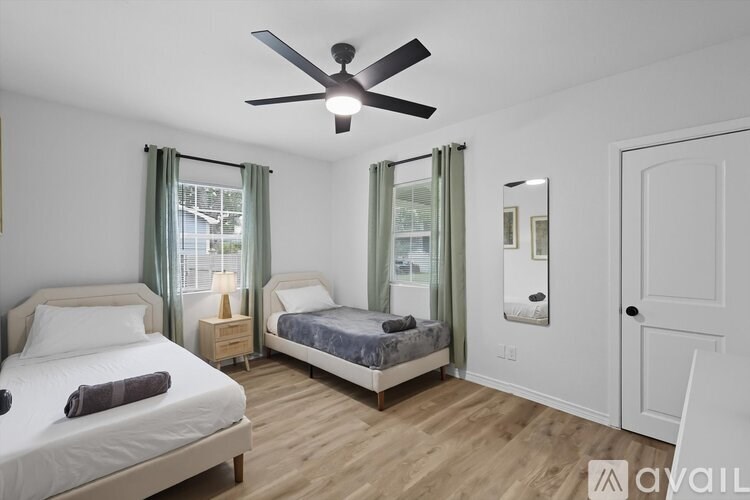 A bedroom with two beds and a ceiling fan.