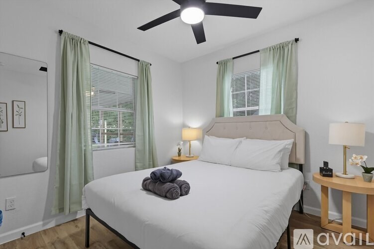 A neatly made bed with a white comforter and a folded towel on top.