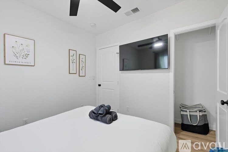 A bedroom with a bed, a ceiling fan, and a mirror.