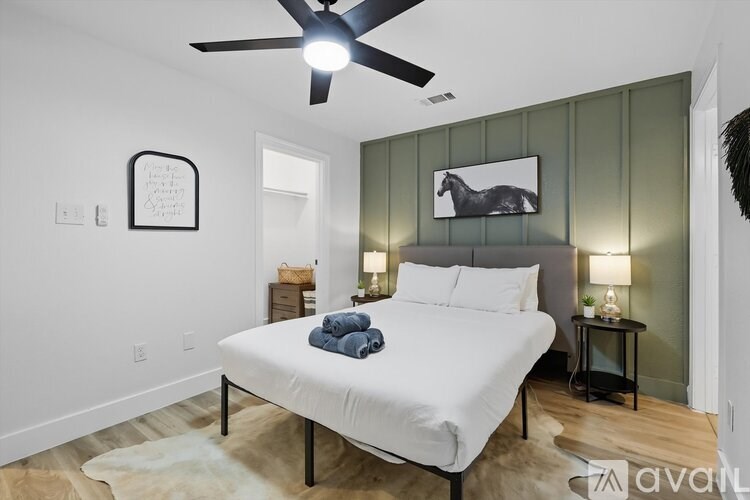 A bedroom with a white bed and a ceiling fan.