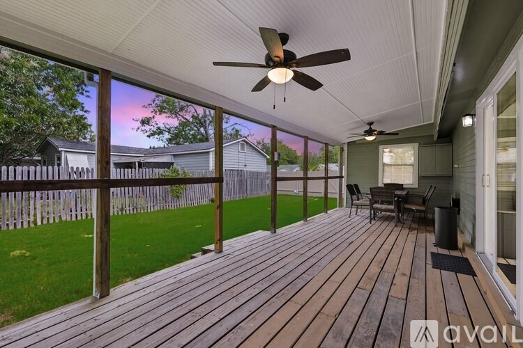 A wooden deck with a ceiling fan and a table.