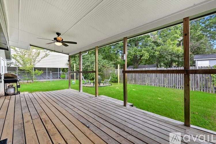 A wooden deck with a ceiling fan and sliding glass doors.
