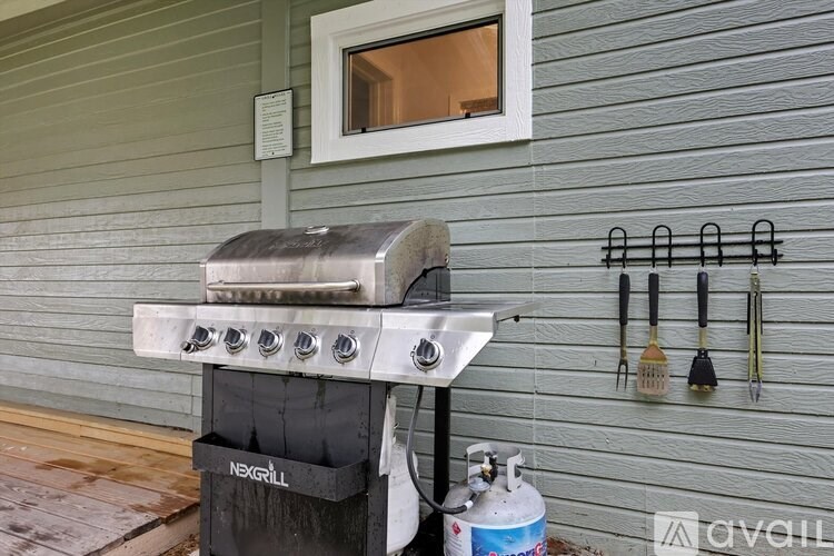 A grill is on a wooden deck next to a wall.