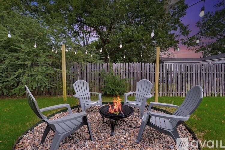 A fire pit surrounded by four chairs in a backyard setting.