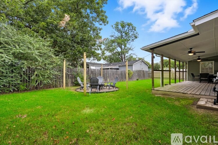 A backyard with a fence, a table and chairs, and a deck.