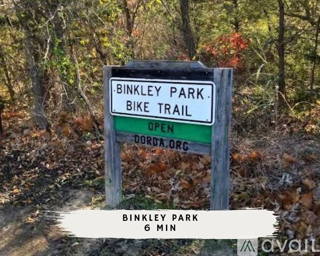 A sign for Binkley Park Bike Trail is displayed in front of a wooded area.