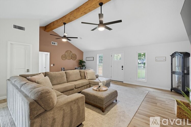 A living room with a brown couch and a ceiling fan.