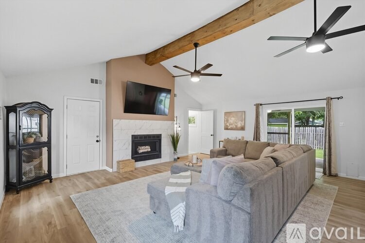 A living room with a grey couch and a fireplace.