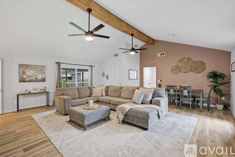A living room with a grey sofa set and a wooden ceiling fan.