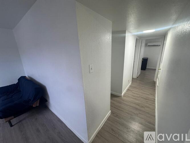 A person is sleeping on a bed in a room with a white wall and wooden floor.