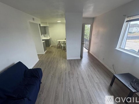 A living room with a blue couch and a wooden floor.