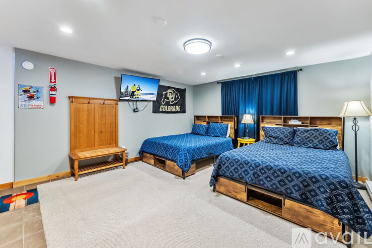 A bedroom with two beds and a TV mounted on the wall.