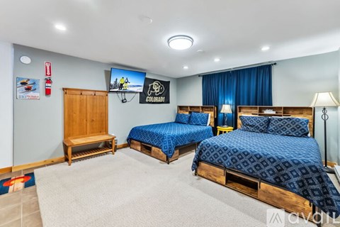 A bedroom with two beds and a TV mounted on the wall.