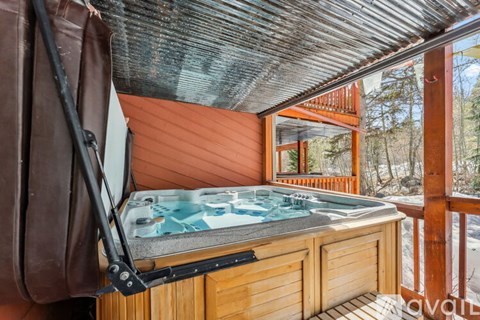 A hot tub is on the balcony of a cabin.
