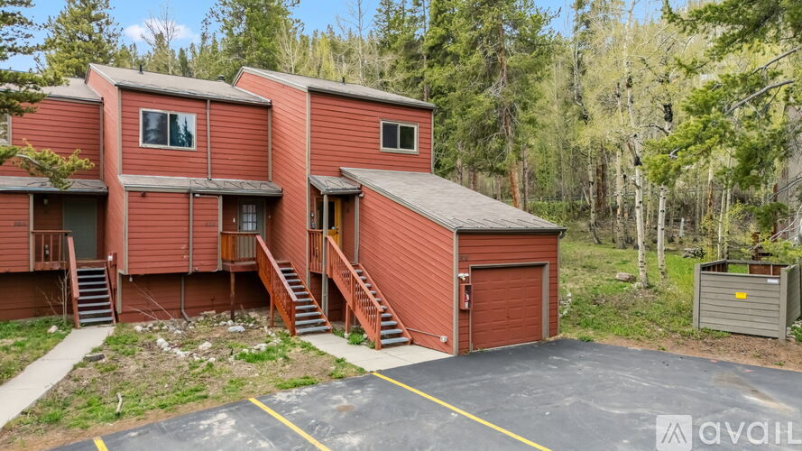 A red building with a garage door is surrounded by trees.