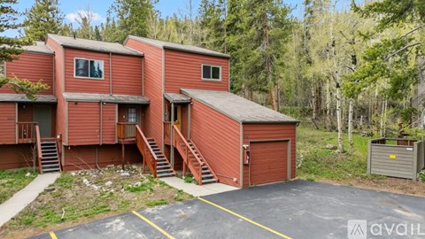 A red building with a garage door is surrounded by trees.