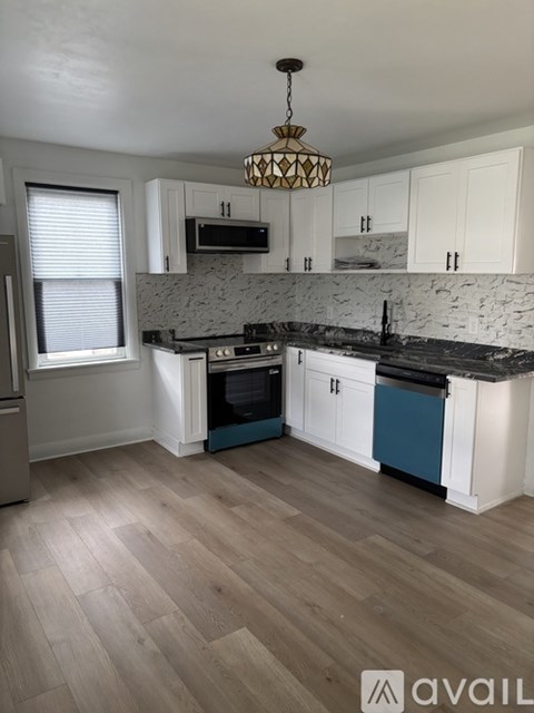A kitchen with a wooden floor and white cabinets.