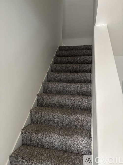 A staircase with a carpeted runner and white walls.