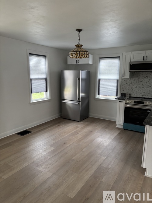 A kitchen with a refrigerator, oven, and a chandelier.