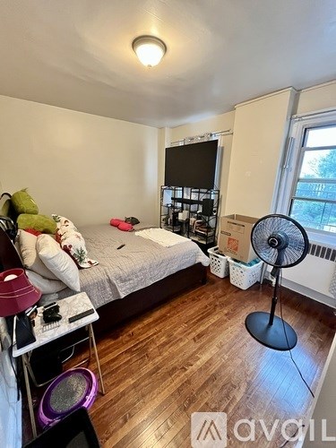 A bedroom with a bed, a fan, and a TV.