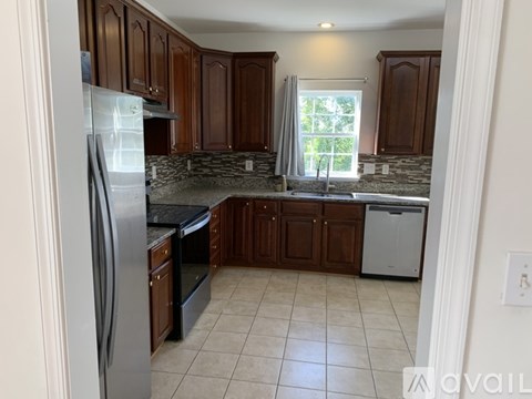 A kitchen with brown cabinets and a stainless steel refrigerator.