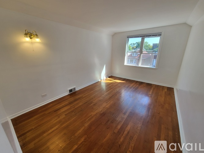 A room with wooden flooring and a window showing daylight.