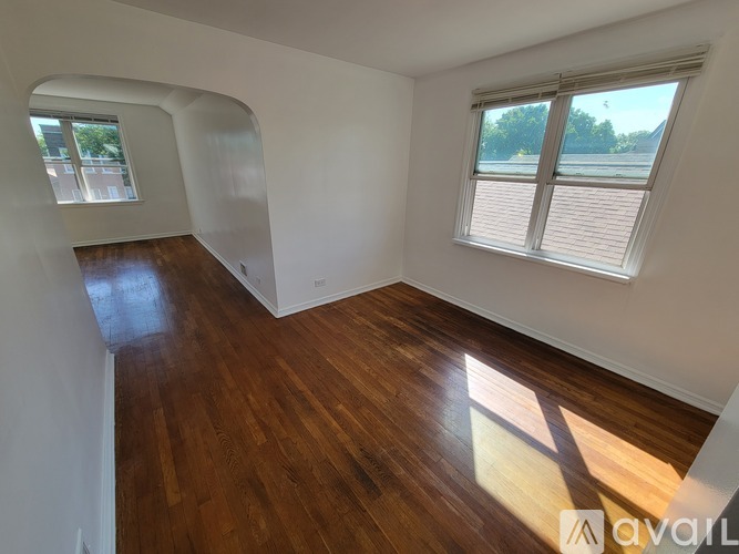 A room with wooden floors and white walls, with a window and a view of trees outside.
