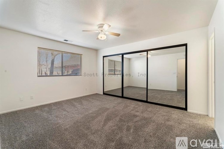 A room with a carpeted floor and a ceiling fan.