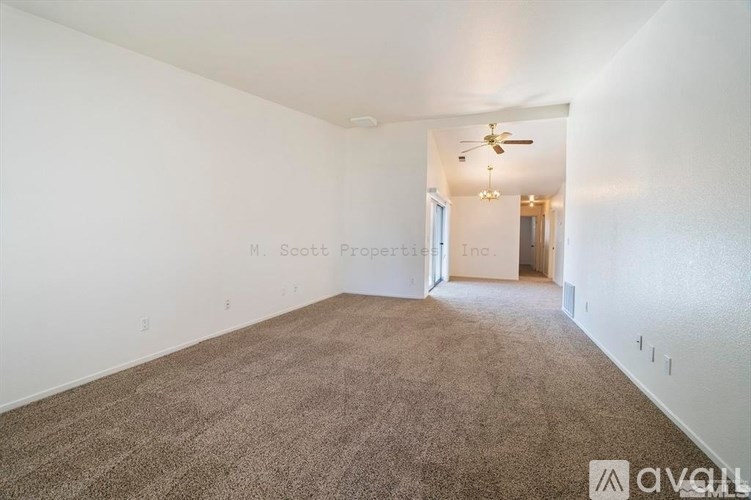 A room with carpeted floor and a ceiling fan.