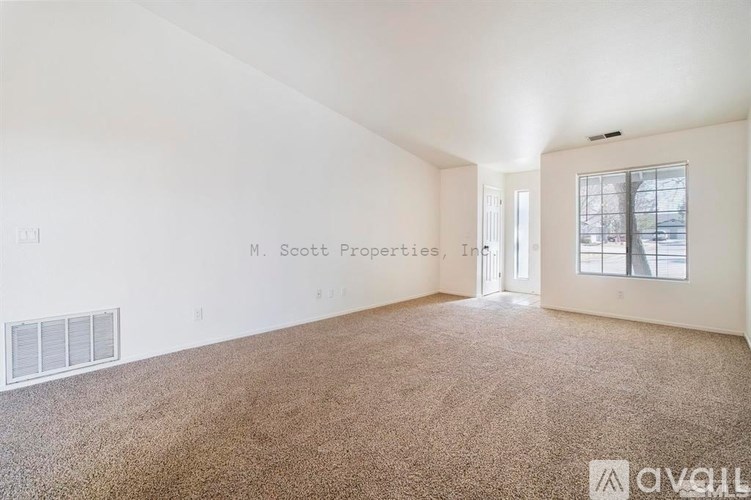 A room with carpeted floor and a window letting in light.